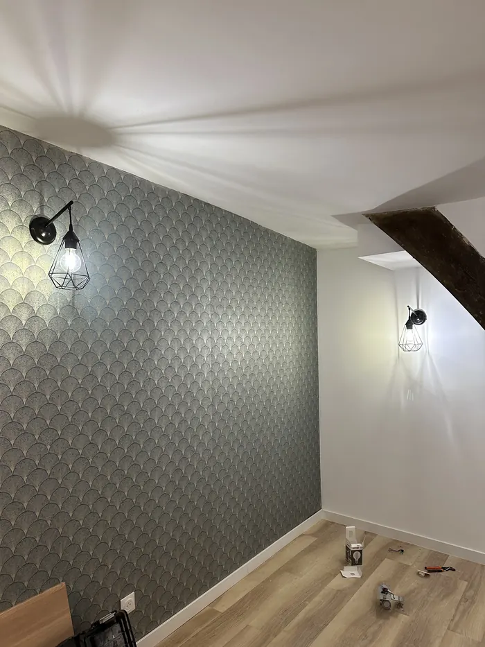 Pose de papier peint à motifs sur un mur de chambre, murs et plafond repeints en blanc