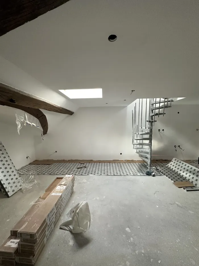 Combles en cours de rénovation : murs et plafonds préparés avant peinture, poutres apparentes