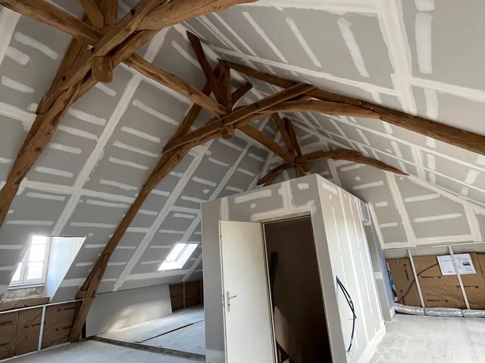 Combles aménagés en placo avec poutres anciennes conservées et bandes réalisées